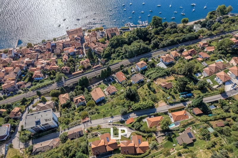 Aerial view of a neighborhood with houses near water, including a swimming pool and views of the sea.