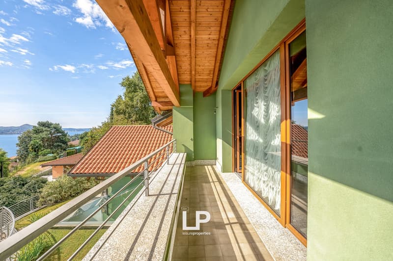 Balcony with wooden ceiling, tiled floor, metal railings, glass doors with curtains