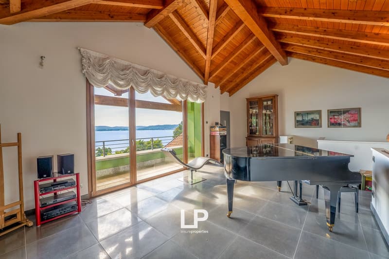 wooden ceiling, sliding glass doors, large glass window, piano, red electronic media stand, chair, balcony, lake view