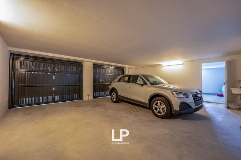 Two garage doors, car parked, entrance leading to washroom