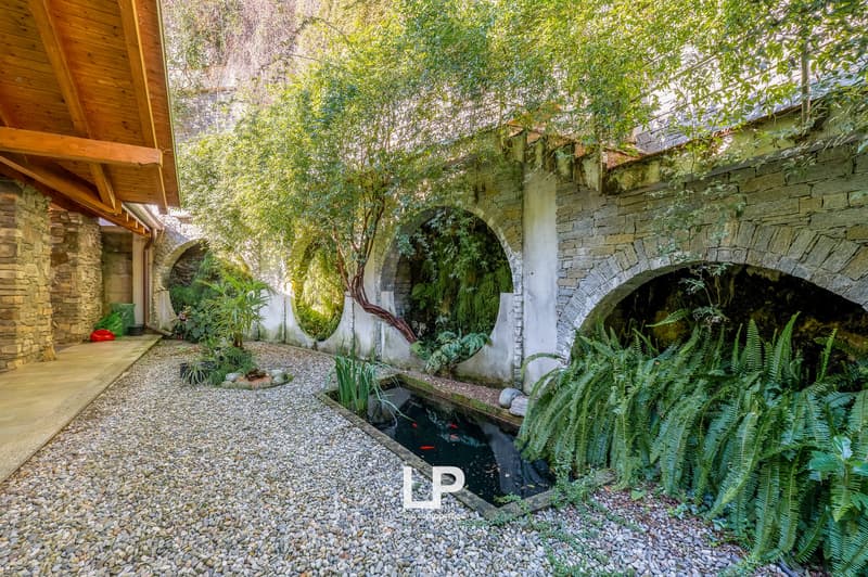 pebble pathway, arched tunnels, fish pond, greenery, plants, small plants in pots, wooden beams