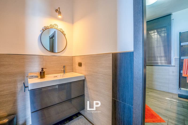 modern bathroom, large mirror, wooden tiles, white sink, stainless steel faucet, blue door, white walls, glass door to shower, light fixture, wooden floors, towel rack