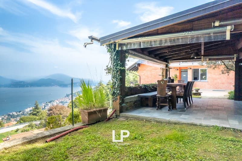covered patio, outdoor dining table and chairs, potted plant, stone walls, paved flooring, overlooking a sea and mountain landscape