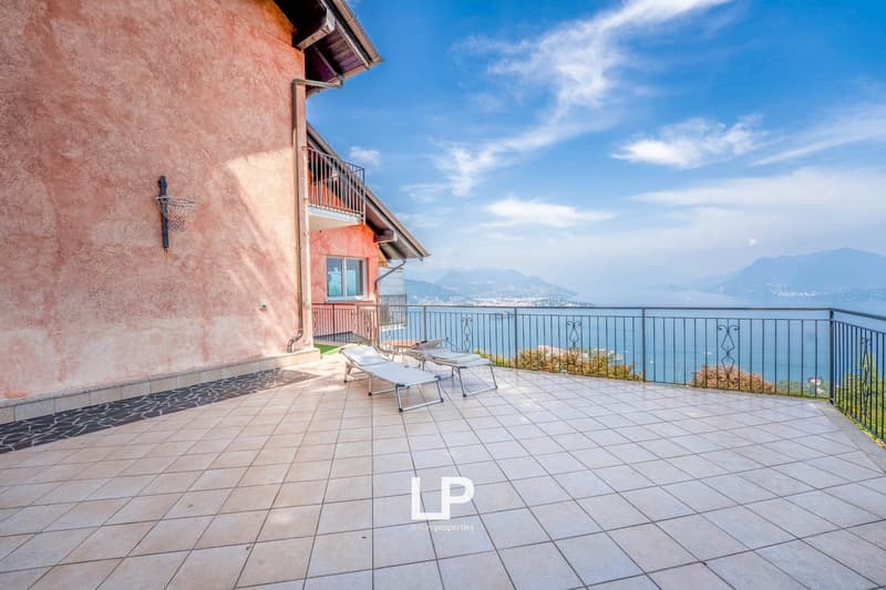tiled floor, black metal railing, lounge chairs, sea view, mountains in the distance