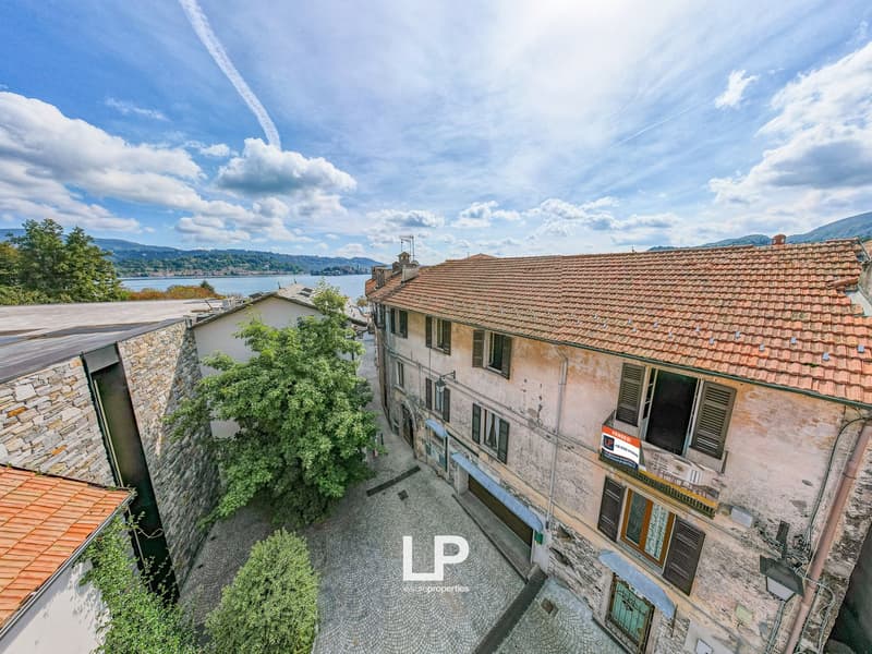 buildings with red roofs and windows, cobblestone street, mountains, lake in the distance