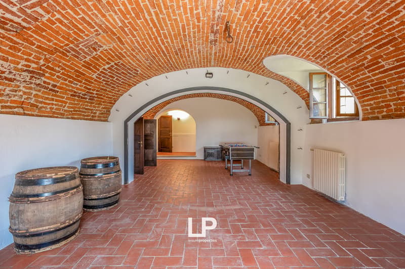Red brick ceiling and walls, red brick floor, wooden barrel on left, table in the center