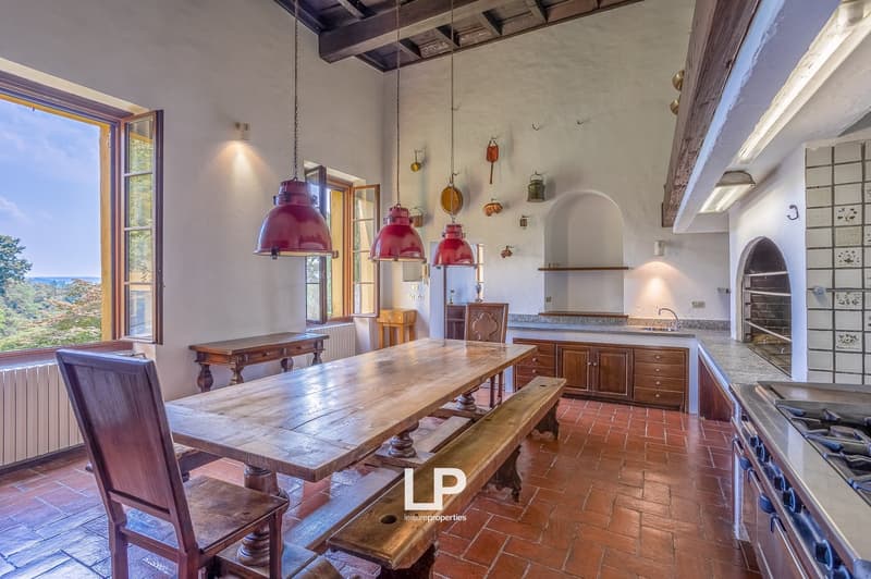 large dining table, wooden benches, wooden chairs, kitchen with gas stove, oven, cabinets, red clay tile floor