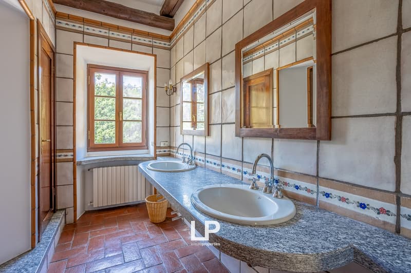 Double sink, marble countertop, wooden window frame, radiator, wicker basket, tiled floor, wooden mirror frames