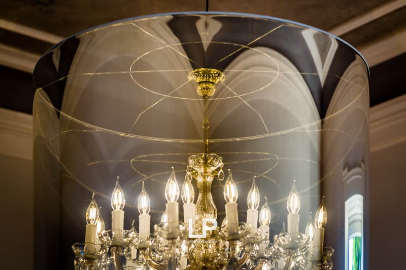 Large chandelier with multiple candles, enclosed in glass dome with geometric design
