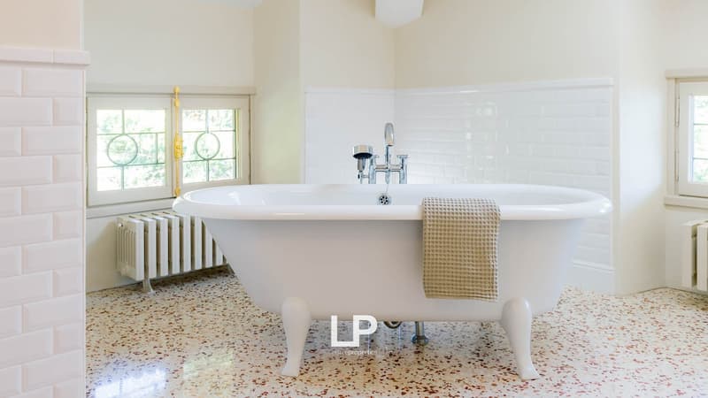 Freestanding bathtub, white tiles, radiator, large windows