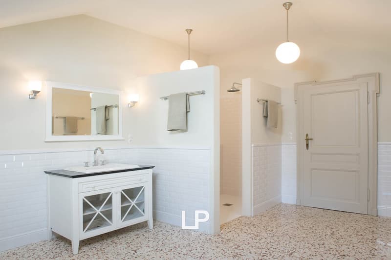 modern bathroom with white tiles, mirror, sink, and shower area