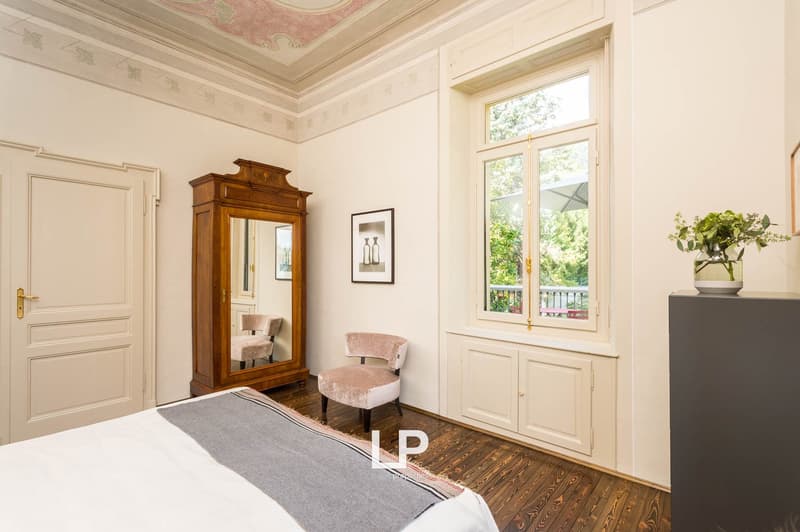 wood floor, double bed, wooden wardrobe, chair, picture frame, window, plant