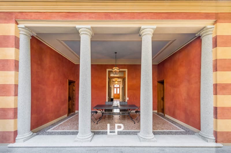 Courtyard, four large columns, marble floor, dining table, red walls, striped columns