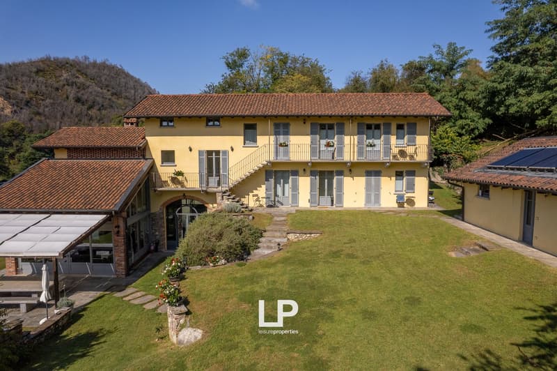 2 story house, yellow exterior, multiple balconies, covered terrace, well-manicured lawn, multiple outbuildings