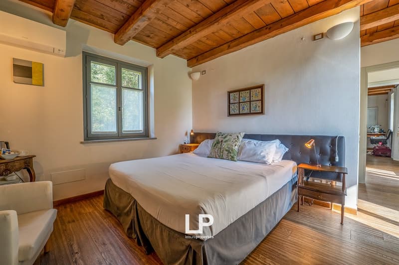 large bed, wooden bed frame, headboard, night tables, lamps, armchair, air conditioning