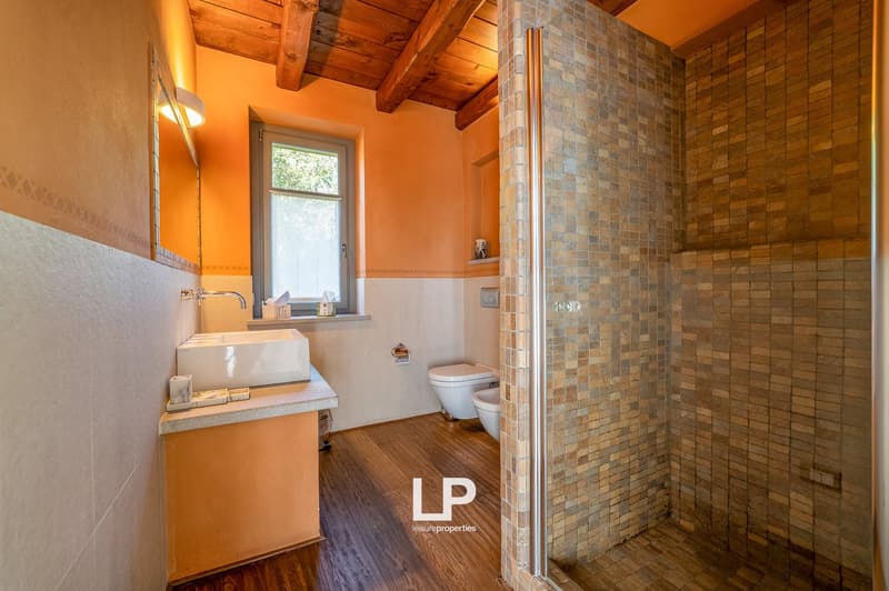 small bathroom with window, toilet, bidet, shower with mosaic tiles, wooden floor