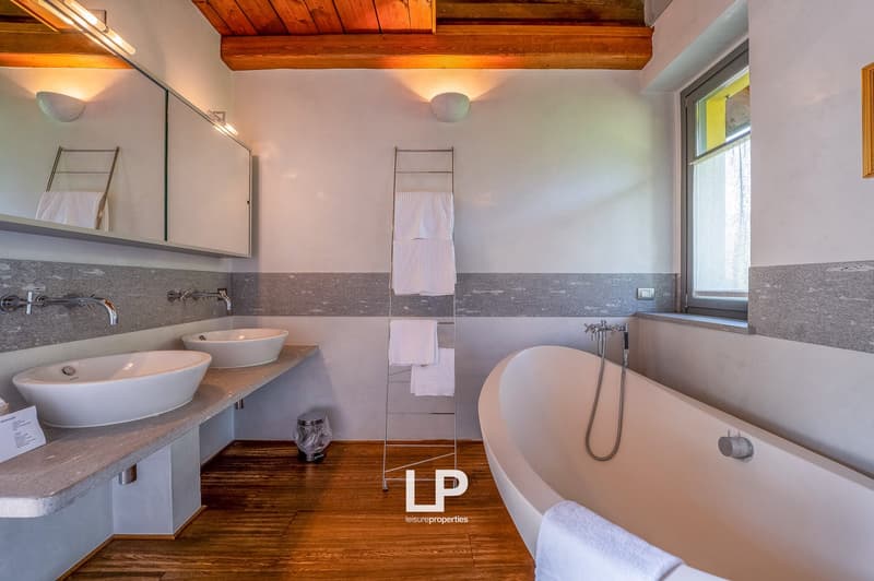 Double sink, separate bathtub, tiled floor, mounted mirror, under cabinet lighting, white fixtures