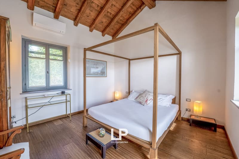 wooden bed, pillows, nightstands with lamps, nightstand with vase, wooden floor, window, picture frame