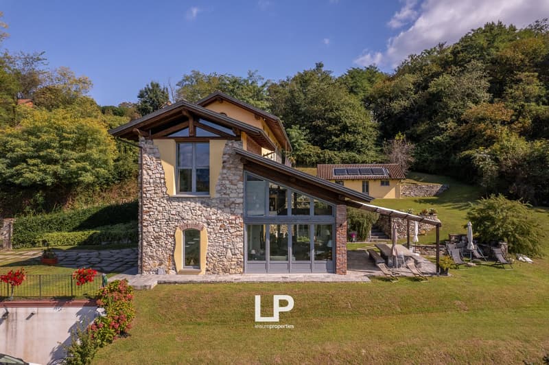 2 story house, stone and glass walls, solar panels, garden with pool and seating area