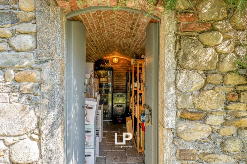 stone wall entrance, archway, wooden shelves, wine bottles, stacked boxes