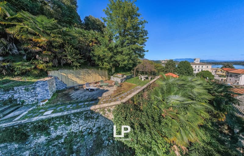 elevated garden with stone walls, lush greenery, gazebo, outdoor seating, stone steps, terraced area
