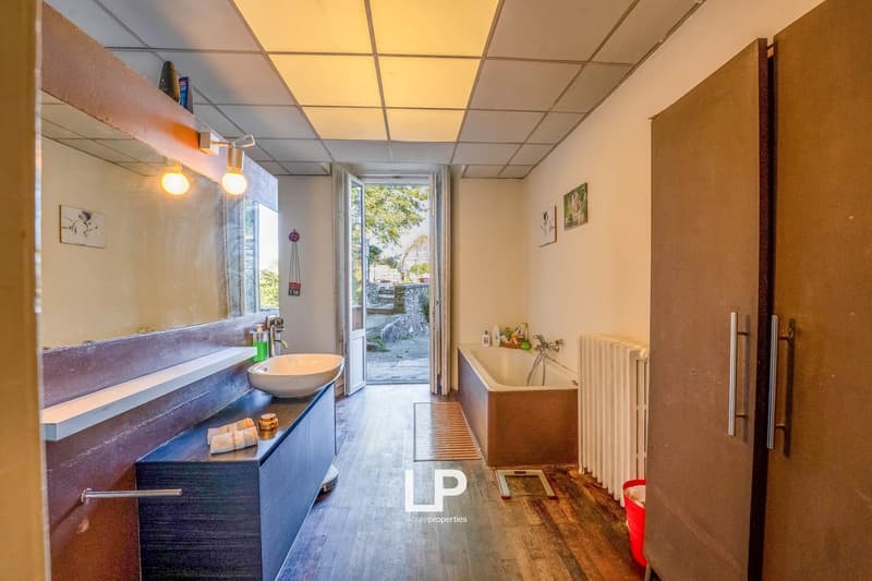 Sink, bathtub, mirror, radiator, towels on counter, doorway to balcony