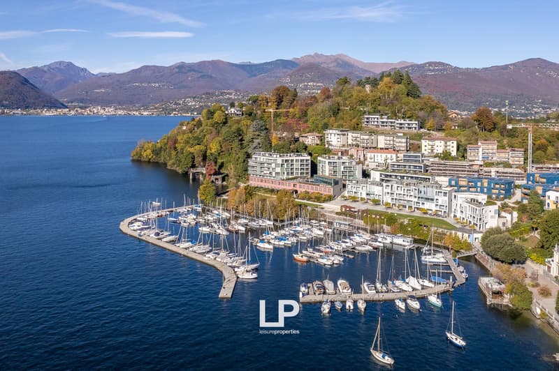 Harbour with boats, buildings with modern architecture, surrounded by nature, mountains in the background, a lake