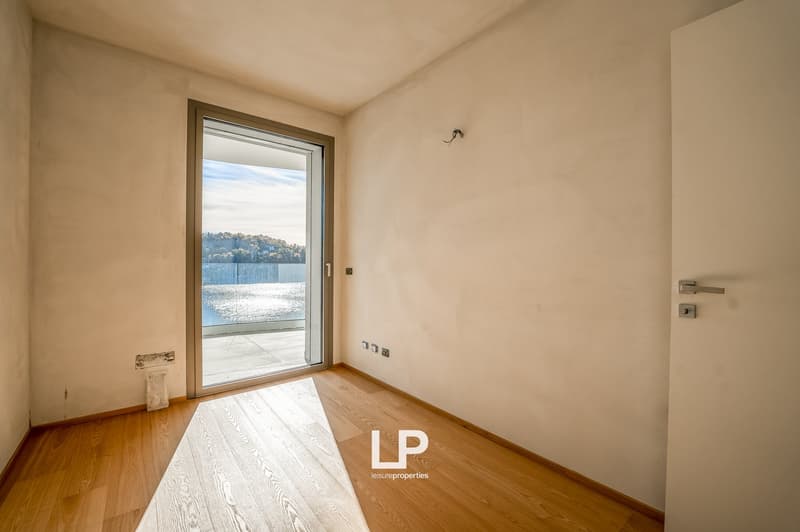 empty room, large glass door leading to balcony, wooden floor, white walls, exterior view