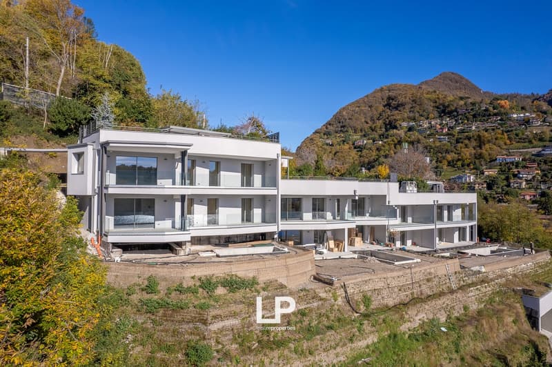 Multi-story building with modern architecture, large glass windows, balconies, swimming pool, surrounded by greenery