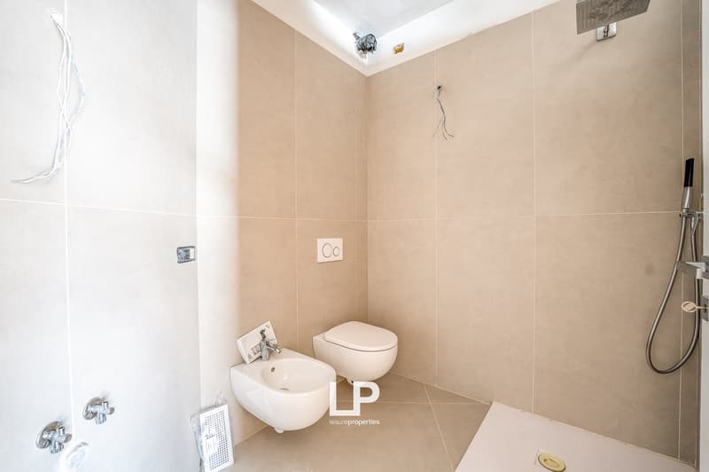 modern bathroom with beige tiles, toilet, bidet, and shower