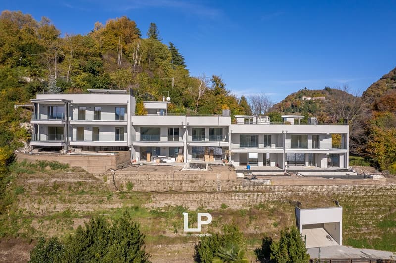 White modern apartment complex with balconies and terraces, set on a hill with beautiful views.