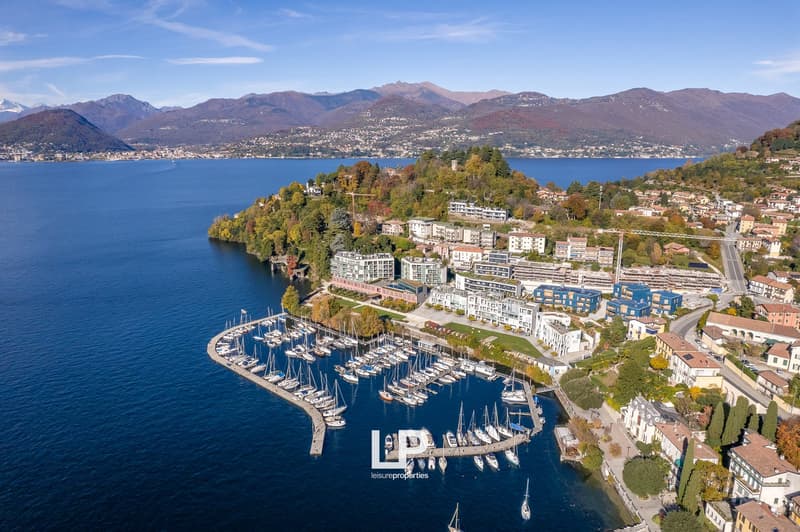 aerial view of harbor, several buildings, mountains in the background, sailboats docked