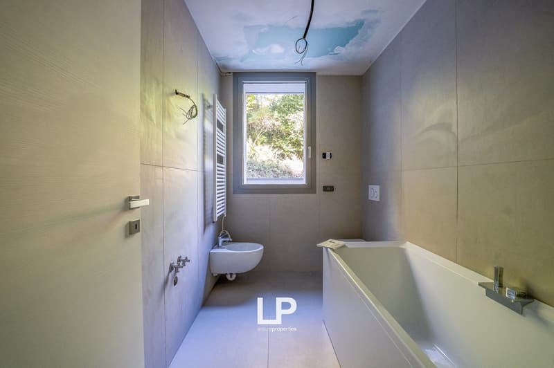 White bathroom with bathtub, sink, window, and towel rack