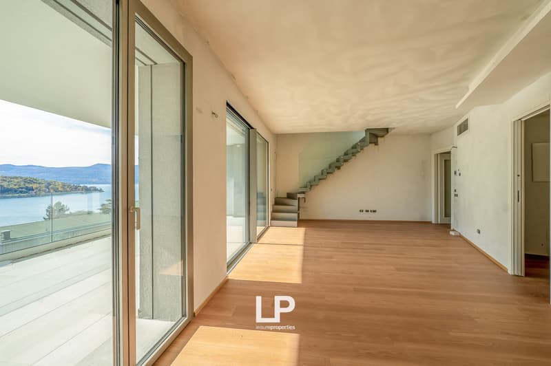 Sliding glass doors, hardwood floors, glass staircase, glass railing, large windows, lake view, mountains in the distance
