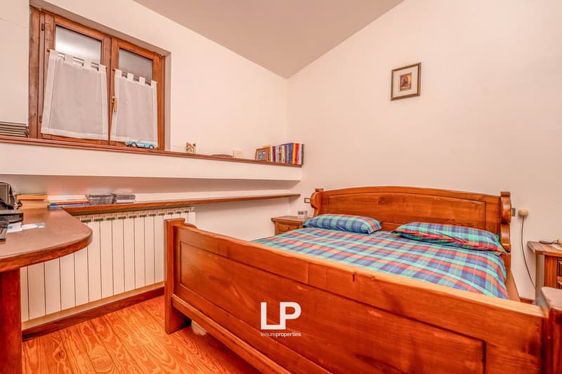 wooden bed, plaid sheets, pillows, night tables, wooden desk, large window, curtains, radiator, books, toy car
