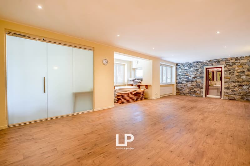 large, empty room with sliding doors, wooden floor, white walls, window, stone wall