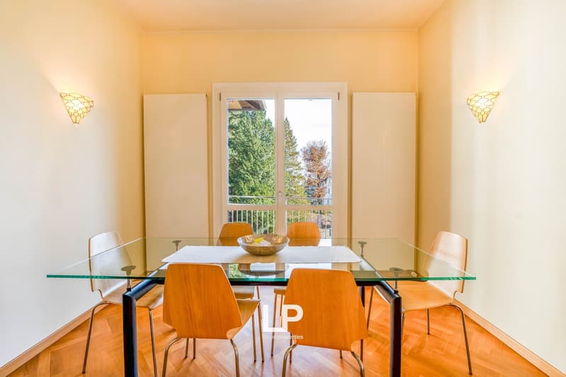 glass table, glass chairs, a bowl on table, sliding glass doors, wall lamps, balcony