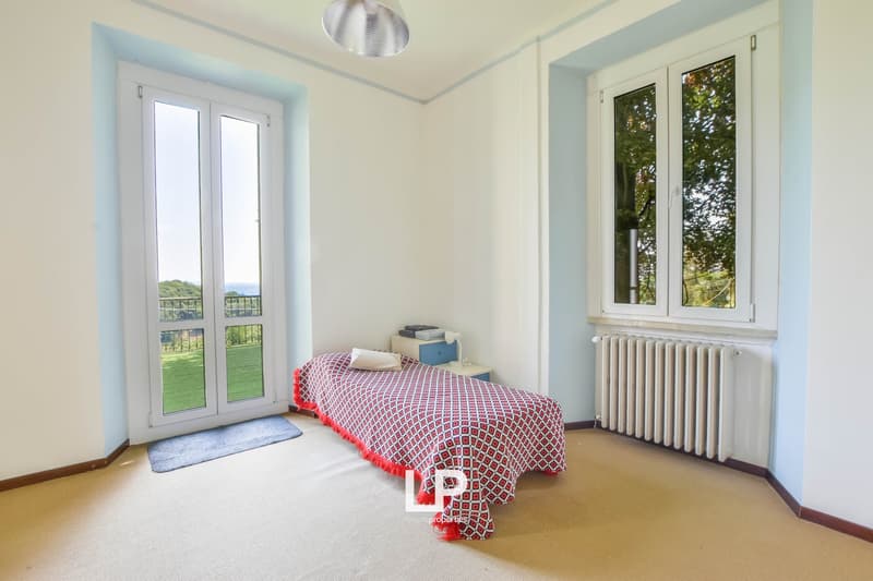 a bedroom with a single bed, a nightstand, a lamp, and a radiator