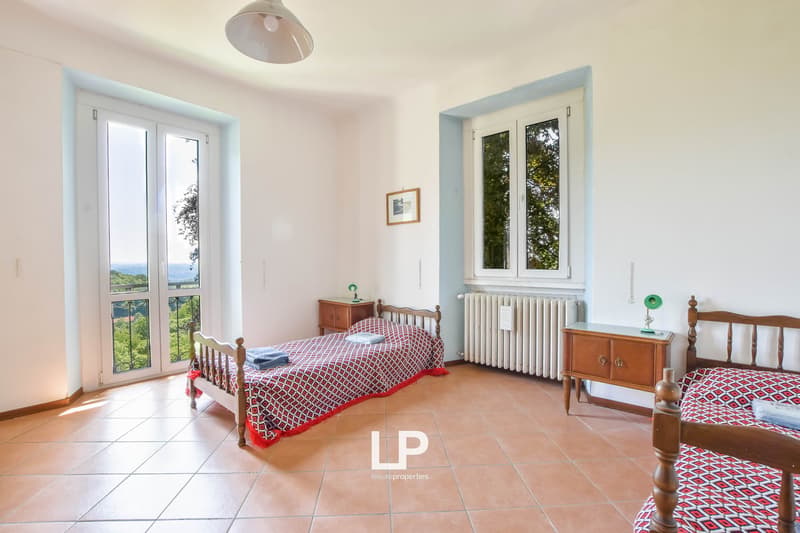 Double room with two single beds, balcony, windows, radiator, wooden nightstand, radiator, framed picture, tiled floor