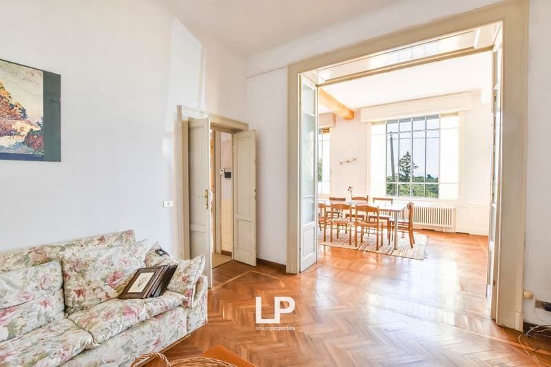Living room, wooden floor, large windows, sofa with pillows, dining table with chairs, dining area with wooden floor, wall mounted radiator, parquet flooring