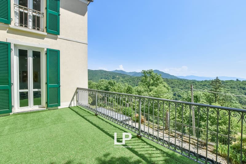Green carpeted terrace with wrought iron railings, green shutters, beautiful panoramic view of mountains