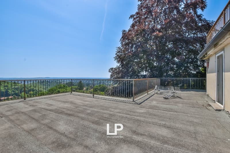 open terrace with railings, metal folding chairs, distant landscape, trees