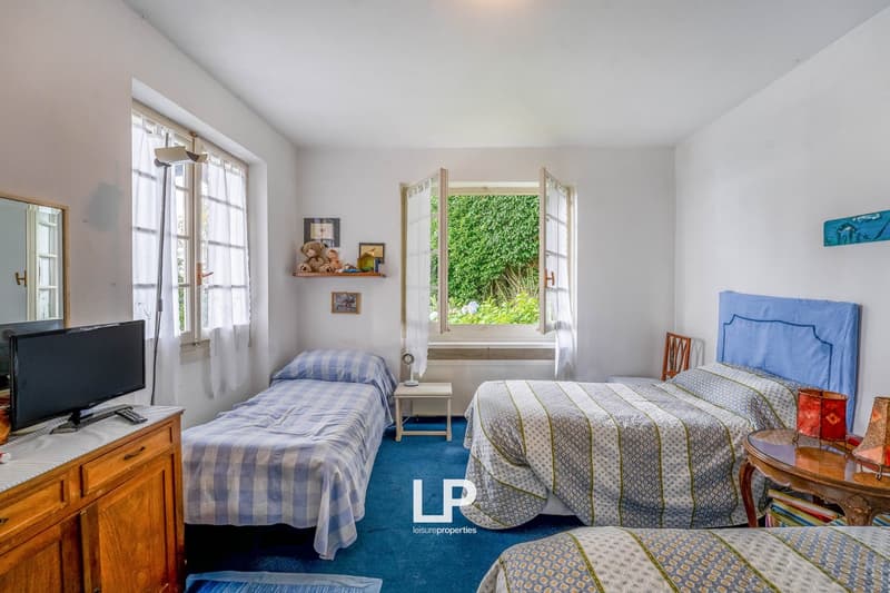 Three twin beds, night stands, a wooden cabinet with TV, carpets, window with view