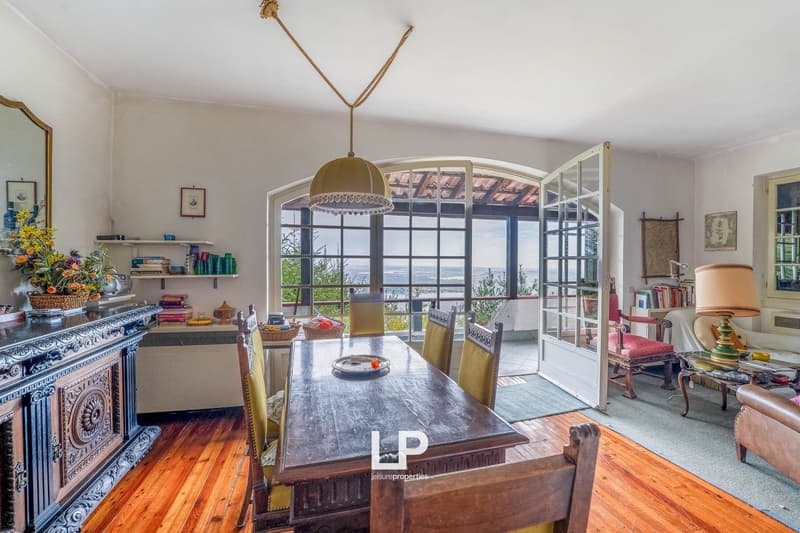 Dining table with 6 chairs, windows with city view, ornate cabinet, lamps, chairs, open door