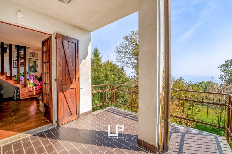 Balcony with brick flooring, wooden door, metal railing, and a scenic view
