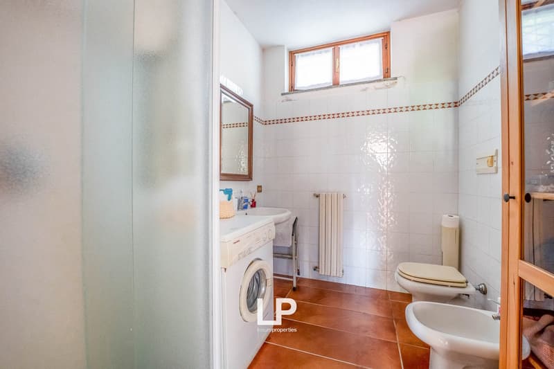 white tiled walls, white ceramic toilet, bidet, white ceramic sink, washing machine, mirror, white radiator