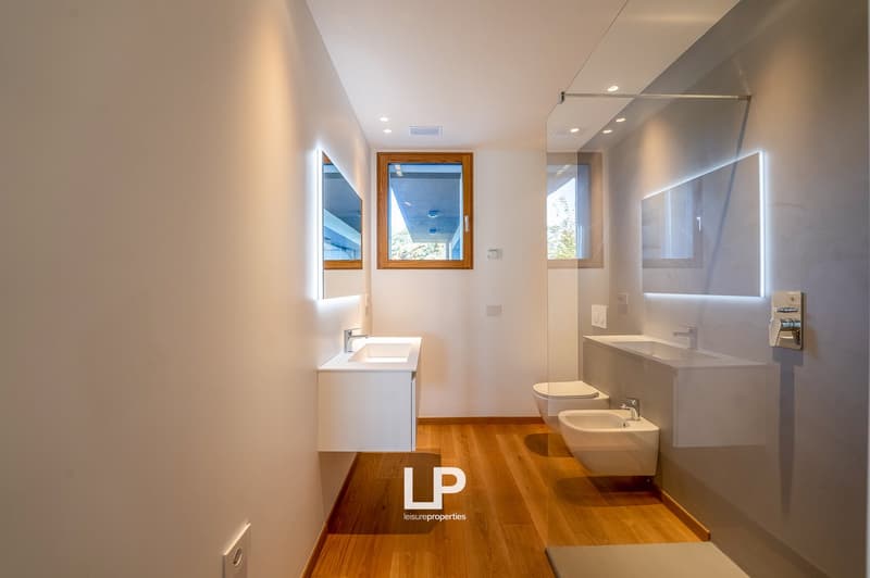 modern bathroom, white walls, wooden floor, two sinks, toilet, shower, two mirrors, windows