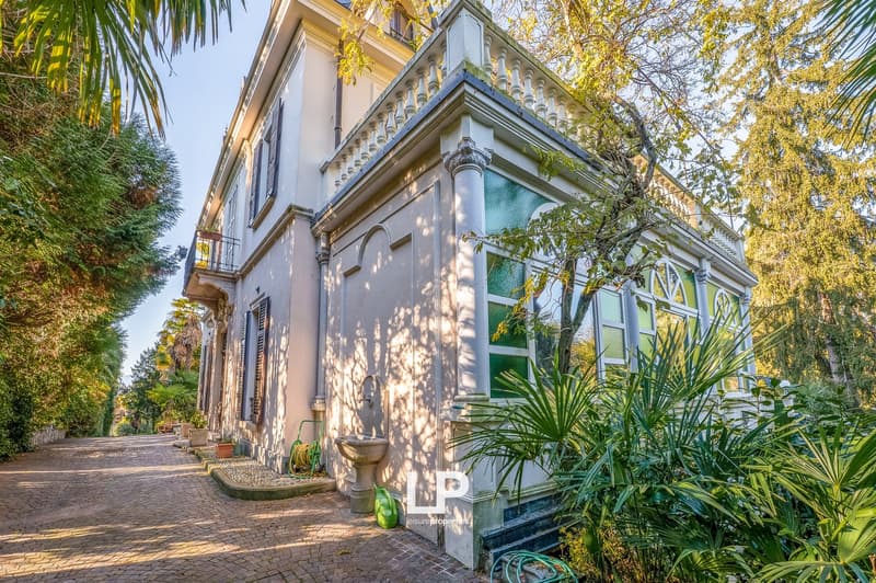 Two-story house, classic architecture, balcony on the second floor, paved driveway, greenery surrounding