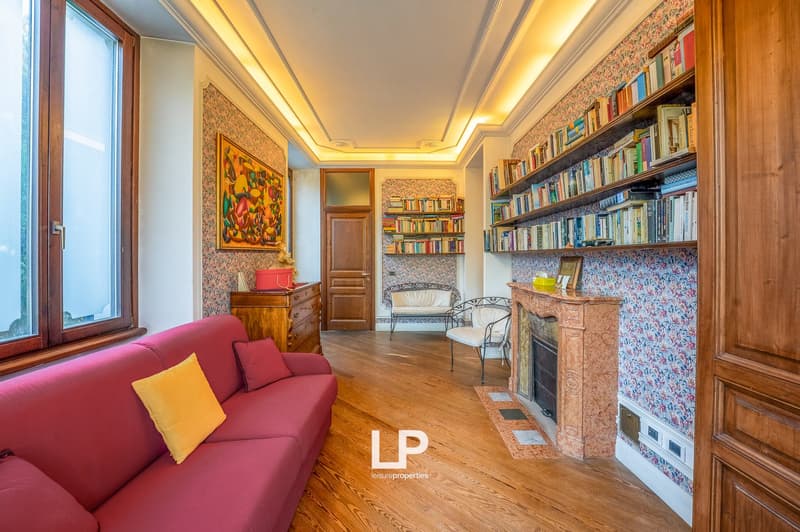 Fireplace, wooden floor, couch, bookshelves, painting, window