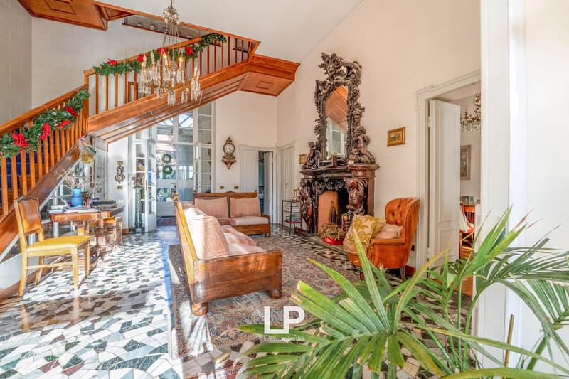 mosaic tiled floor, fireplace, chandelier, wooden staircase, armchairs, couch, side table